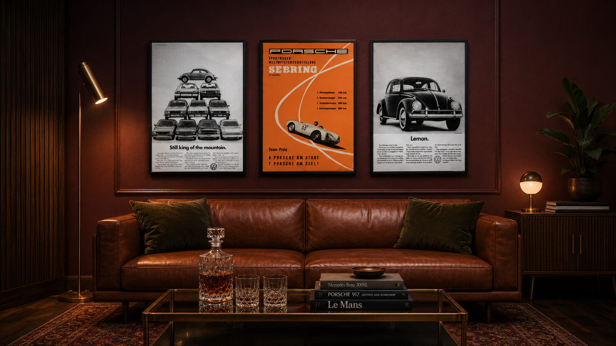Three framed vintage racing posters in a row above a chesterfield leather sofa — Porsche Sebring centred, flanked by vintage VW Beetle ads — The Car Posters